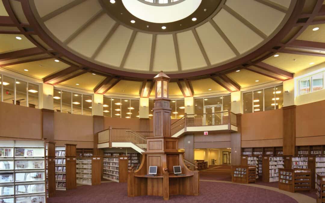 Interior of library rotunda with shelves of books and computer kiosks beneath a skylight